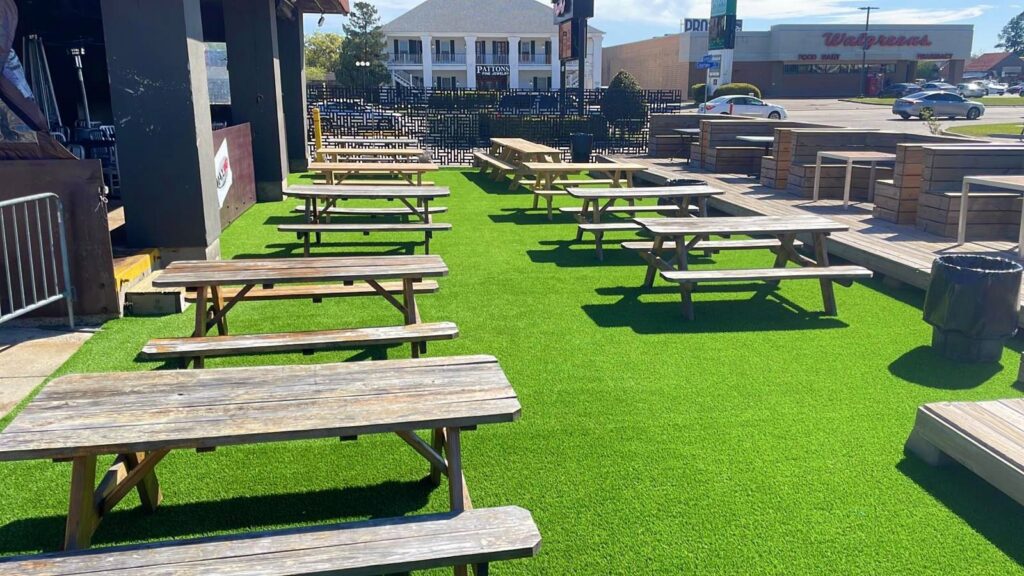 An outdoor patio area with artificial turf and picnic tables installed by Carpet World Baton Rouge, LA.