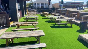 An outdoor patio area with artificial turf and picnic tables installed by Carpet World Baton Rouge, LA.