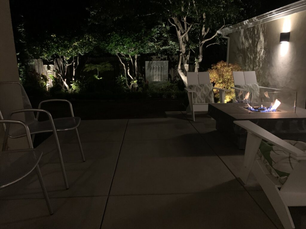 An outdoor patio featuring a fire pit and elegant accent lighting by The Lighting Geek in Sacramento, CA.