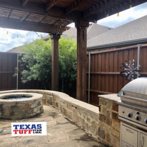 An inviting outdoor patio with a fire pit, grill, and a freshly stained wood fence by Texas Tuff Stain and Seal in Fort Worth, TX.
