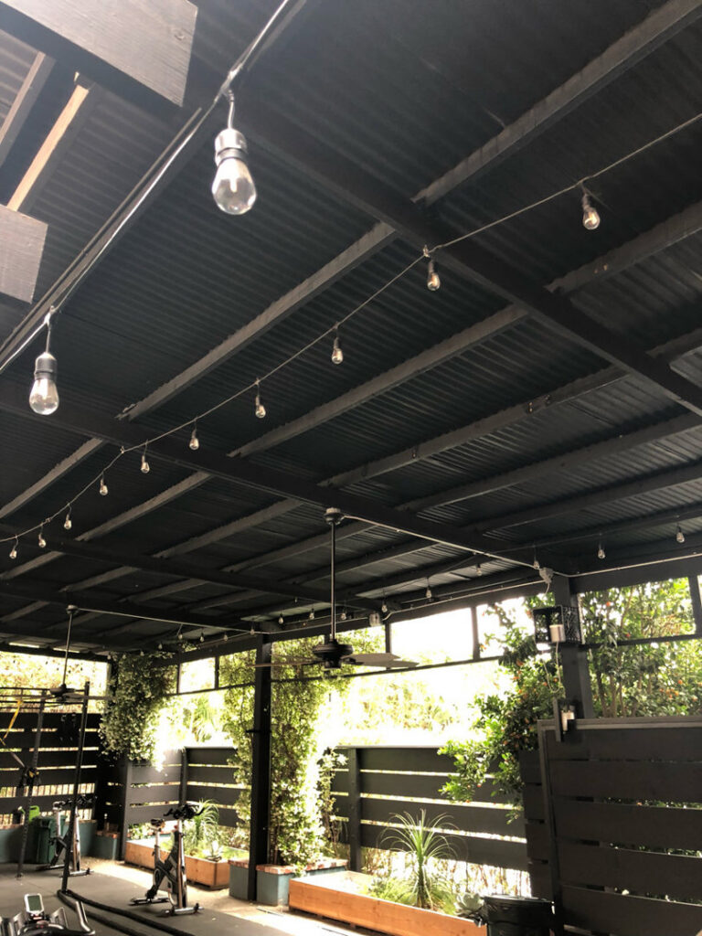 Outdoor patio with string lights and a ceiling fan installed under a roof by Prime Electric in Bellevue, WA.
