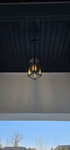 A stylish outdoor pendant light fixture installed under a porch ceiling by Midway Electric in Columbia, MO