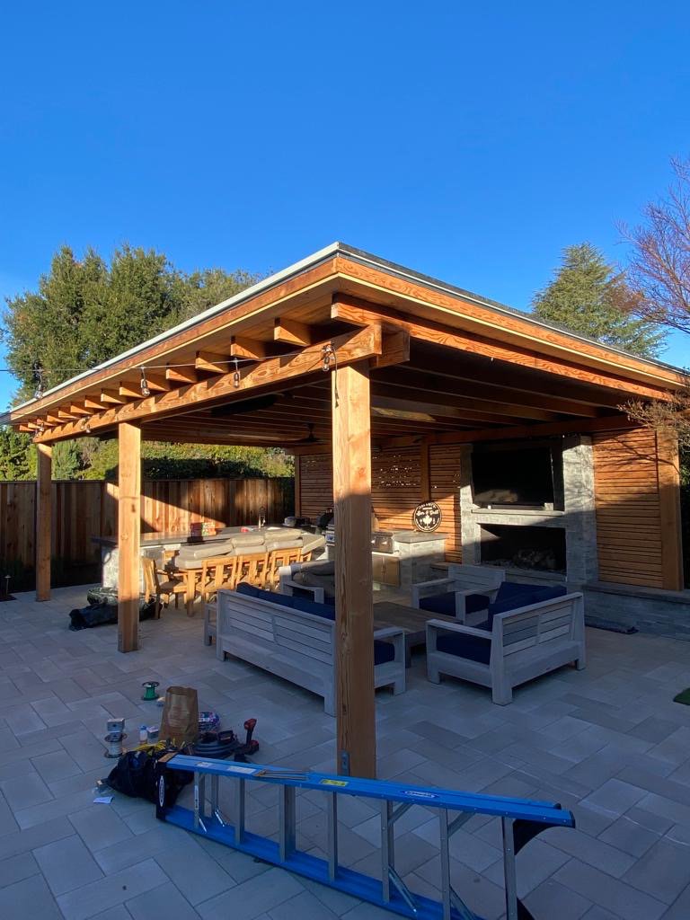 An outdoor pergola with a slatted wood privacy fence by Jaz Builders Inc in Santa Clara, CA.