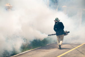 A technician performing outdoor pest fogging, creating a large cloud of mist for Eco Advantage Termite and Pest Solutions in Fayetteville, NC