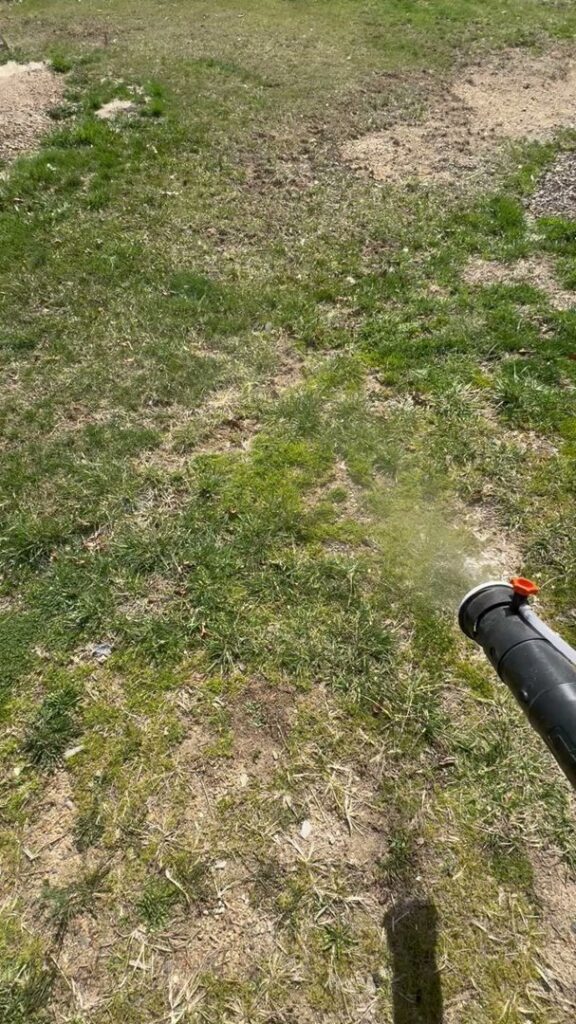 A pest control technician using a sprayer for outdoor pest treatment on a lawn by PestGoat, llc. in Fort Ashby, WV.
