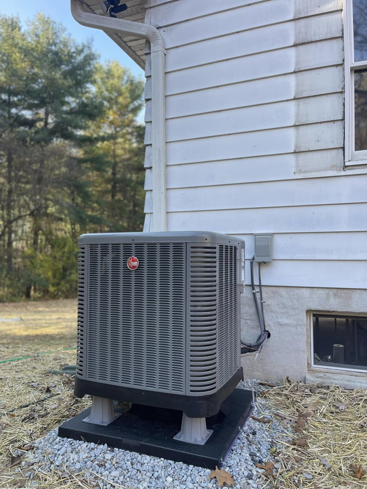 An outdoor Rheem air conditioning unit installation next to a residential building by Force Mechanical Services in Churchville, MD.