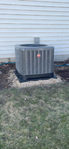 An outdoor Rheem air conditioning unit installed next to a residential building by ACW Heating & Air in North Aurora, IL