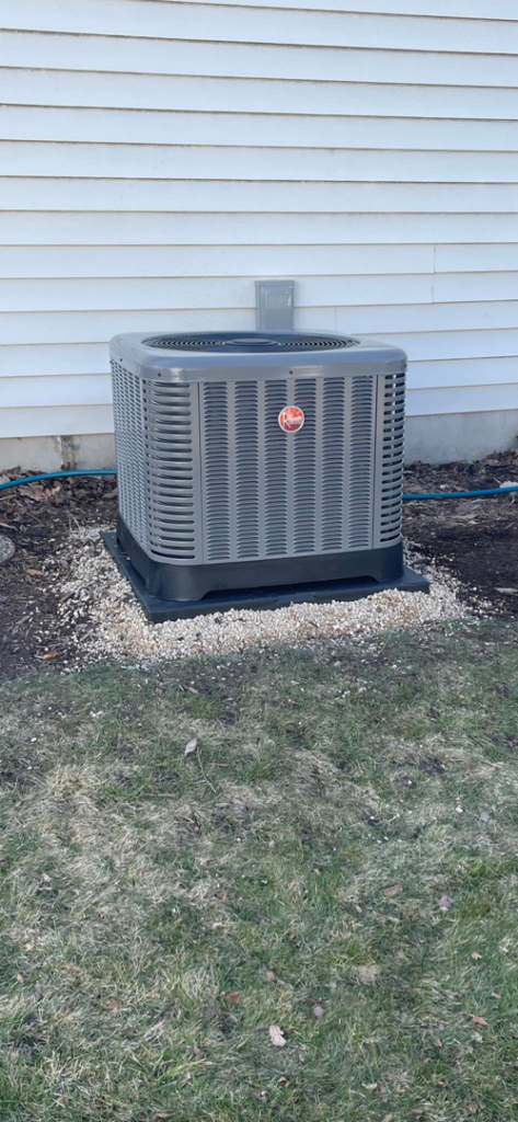 An outdoor Rheem air conditioning unit installed next to a residential building by ACW Heating & Air in North Aurora, IL