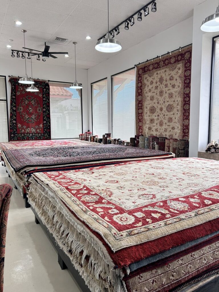 An outdoor tent display showcasing various rugs from Ebie's Rug Cache & Ebie's Rug Cleaning at an event in Tucson, AZ