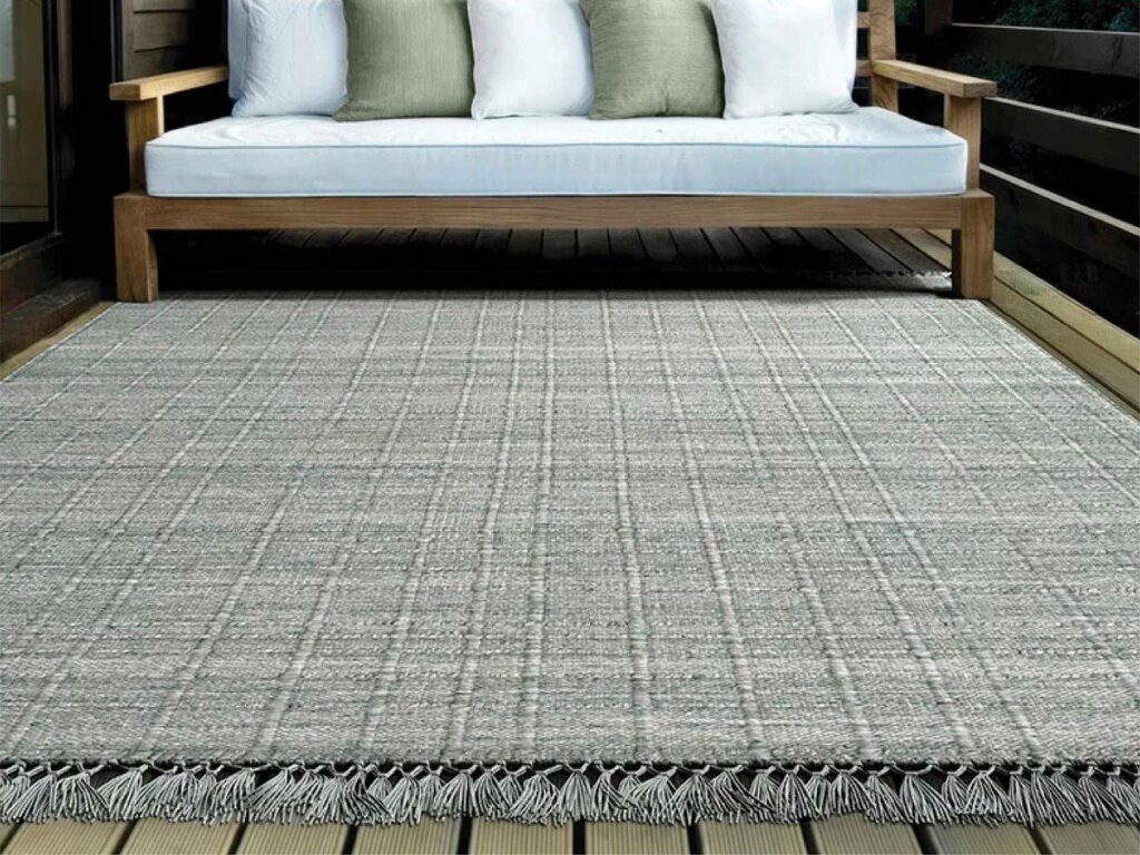 A durable outdoor rug placed on a wooden deck, available from Morency Flooring in New Bedford, MA.