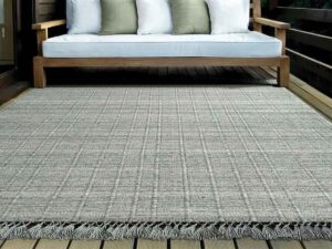 A durable outdoor rug placed on a wooden deck, available from Morency Flooring in New Bedford, MA.