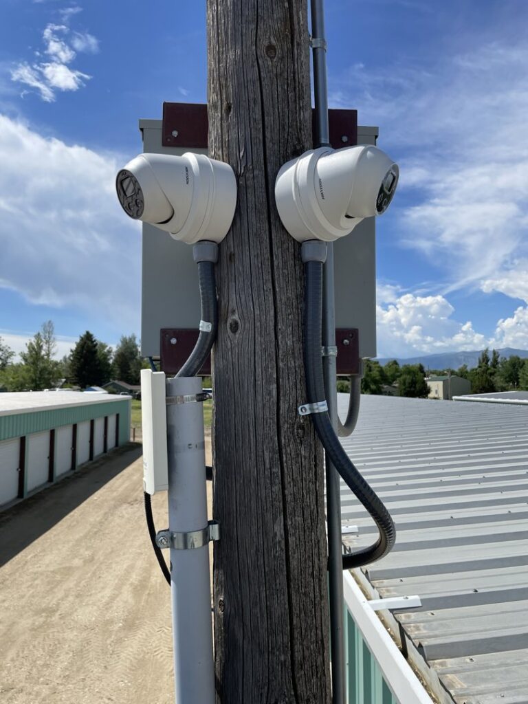 Outdoor security cameras with electrical conduit and wiring installed on a wooden pole by D.B. Smart Homes & Security LLC in Sheridan, WY.