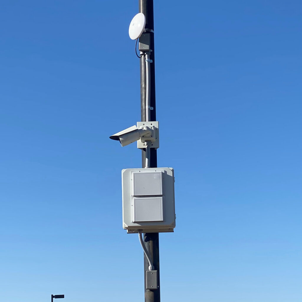 An outdoor pole with a security camera and communication boxes installed by CAAM Integration LLC in Albuquerque, NM.