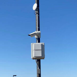 An outdoor pole with a security camera and communication boxes installed by CAAM Integration LLC in Albuquerque, NM.