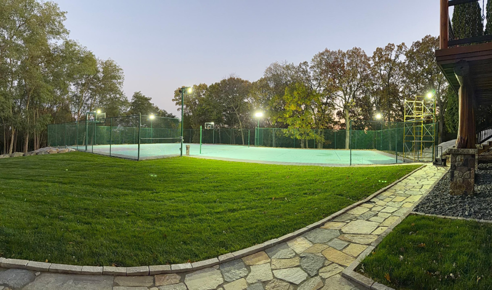 An outdoor sports court illuminated by bright floodlights, showcasing lighting installation by Power Plus Electric LLC in Rochester, MN.