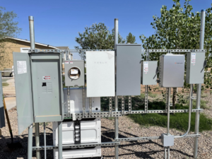 An outdoor electrical setup featuring a Tesla Powerwall and various electrical enclosures, installed by Flores power solutions in El Paso, TX.