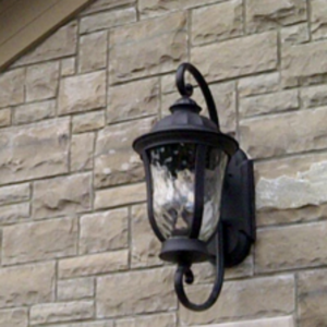An outdoor wall lantern installed on a stone exterior by Hughes Electric in Troy, NY