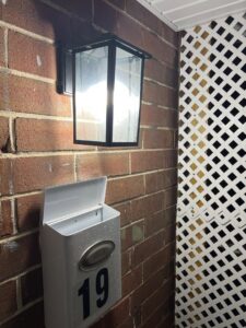 An outdoor wall lantern illuminating a brick wall and mailbox, installed by Mark Anthony Electric LLC in Wilmington, DE