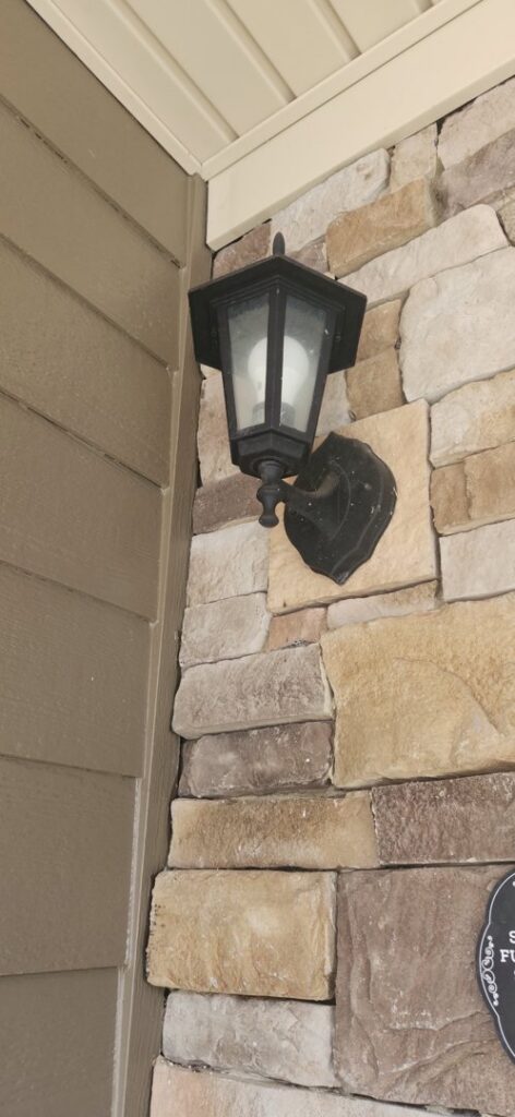 An outdoor wall lantern installed on a stone house by Goodie's Electrical Contractors LLC in Dothan, AL