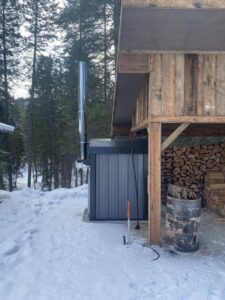 An outdoor wood furnace installed next to a building by Outdoor Wood Furnaces, LLC in Kalispell, MT