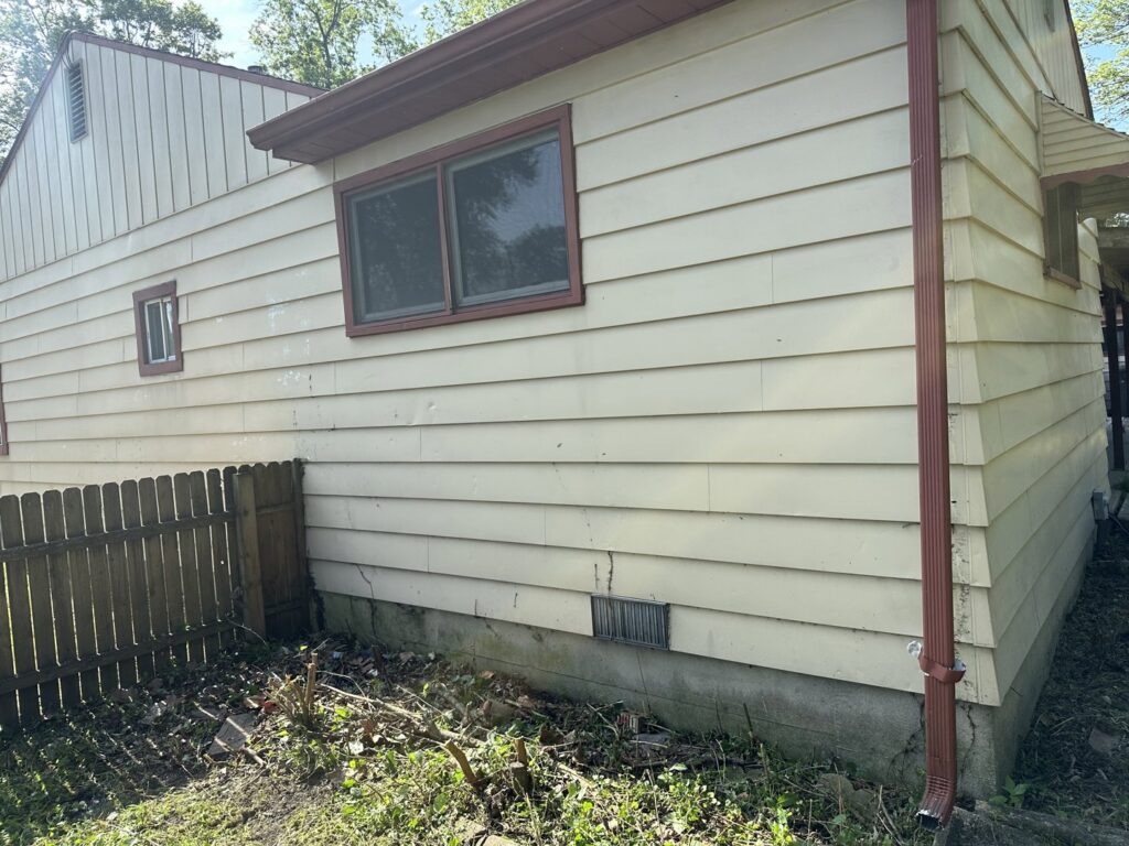 An overgrown area around a house foundation, showing a need for cleanup by Geno's Father & Son Lawn Services Llc in Hammond, IN