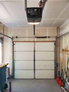 An interior view of a white sectional garage door with an overhead opener, installed by Black Forest Door Repair in Colorado Springs, CO.