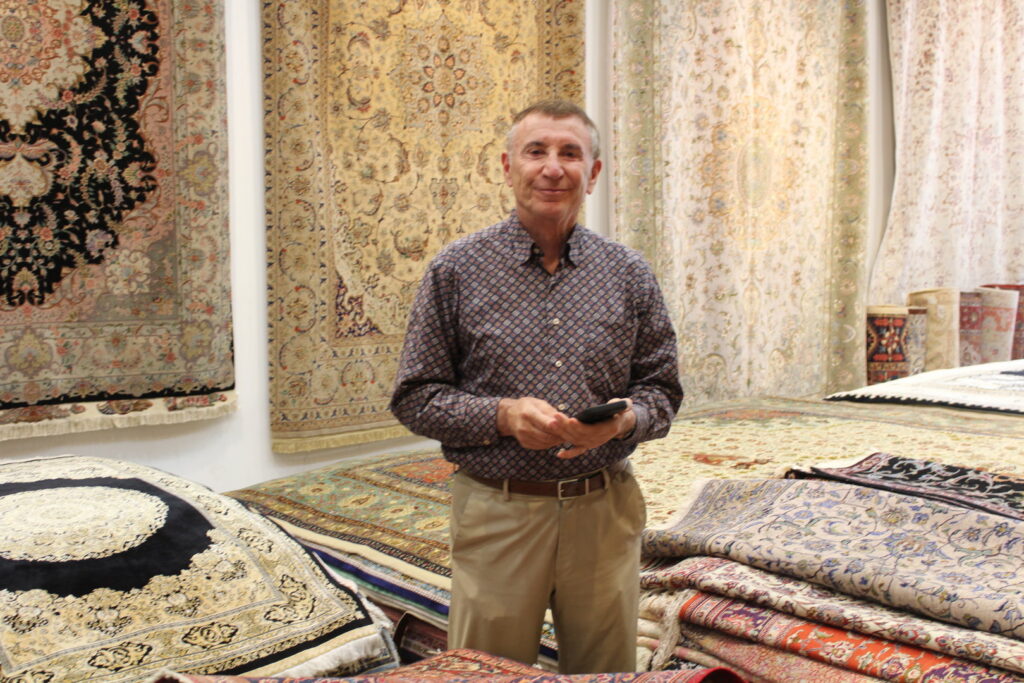 The business owner standing amidst a wide selection of oriental rugs in the Borokhim's Oriental Rugs showroom in Madison, WI.
