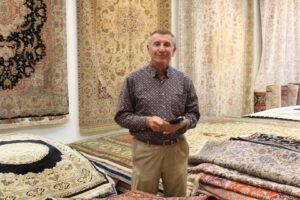 The business owner standing amidst a wide selection of oriental rugs in the Borokhim's Oriental Rugs showroom in Madison, WI.