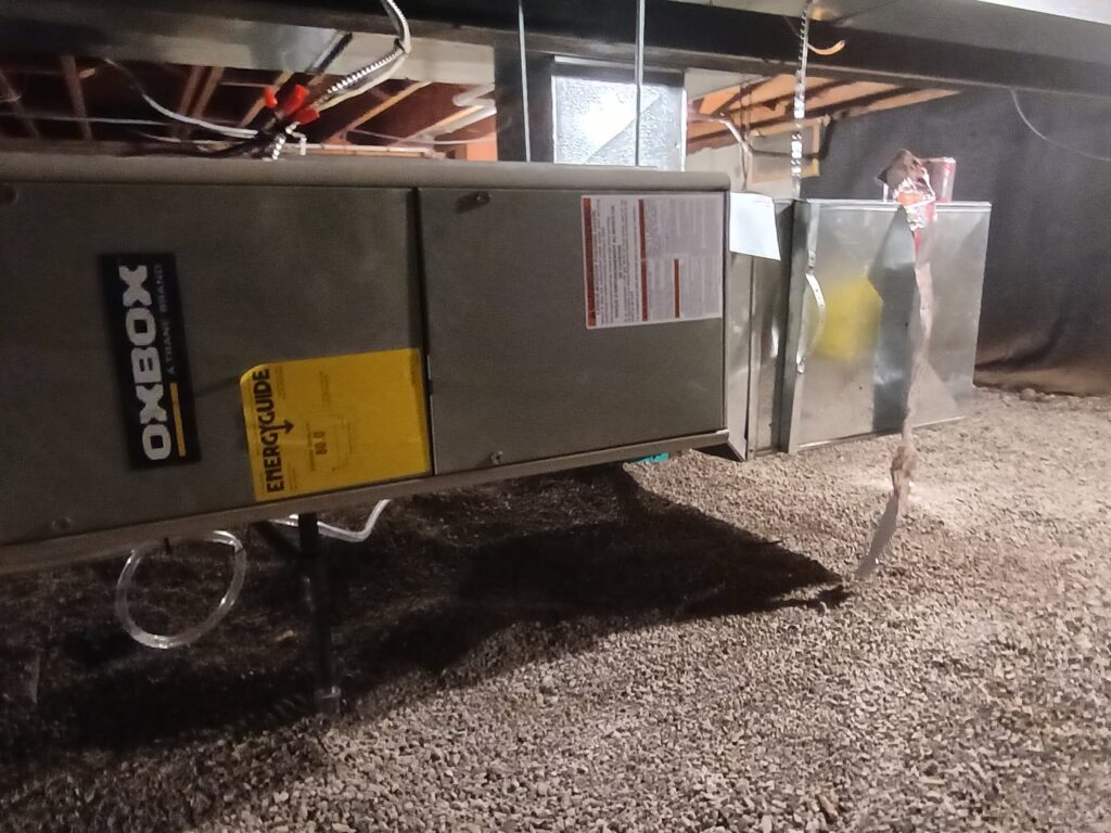 An Oxbox HVAC furnace unit installed in a crawl space or basement, showing work by TAS Mechanical Services in Kearney, MO.