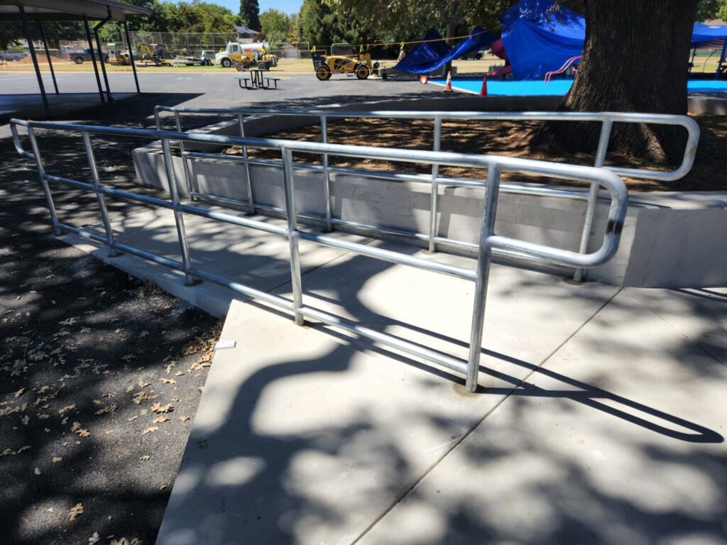A sturdy commercial metal handrail installed along a concrete ramp by Palmers Iron Fence in Sacramento, CA.