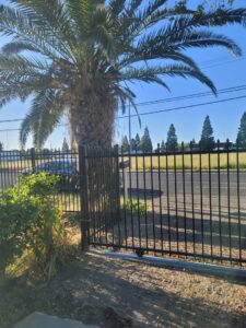 A commercial sliding metal gate and fence providing access control, installed by Palmers Iron Fence in Sacramento, CA.