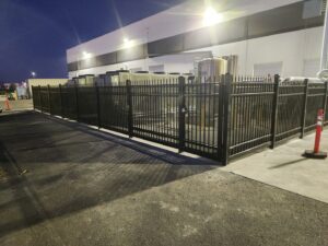 A robust industrial security metal fence protecting equipment at night, installed by Palmers Iron Fence in Sacramento, CA.