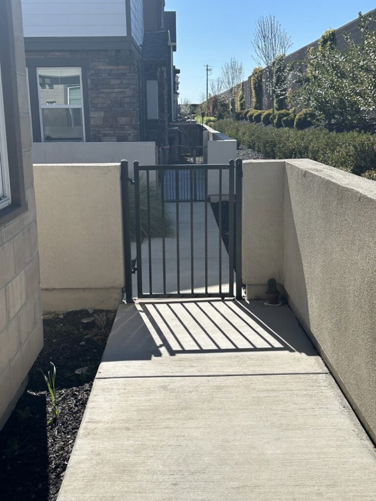 A small metal pedestrian gate providing access between concrete walls, installed by Palmers Iron Fence in Sacramento, CA.