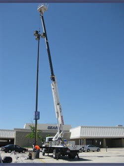 Electrician from TCL Electrical and Lighting repairing a parking lot light pole in North Aurora, IL