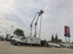 TCL Electrical and Lighting team performing parking lot lighting maintenance with two boom trucks in North Aurora, IL