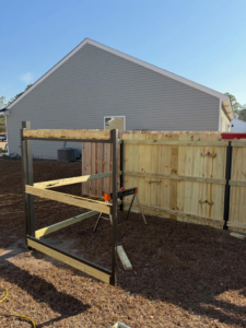 A partially constructed wooden fence with black metal posts in a backyard by JBunlimitedfencingllc in Savannah, GA.