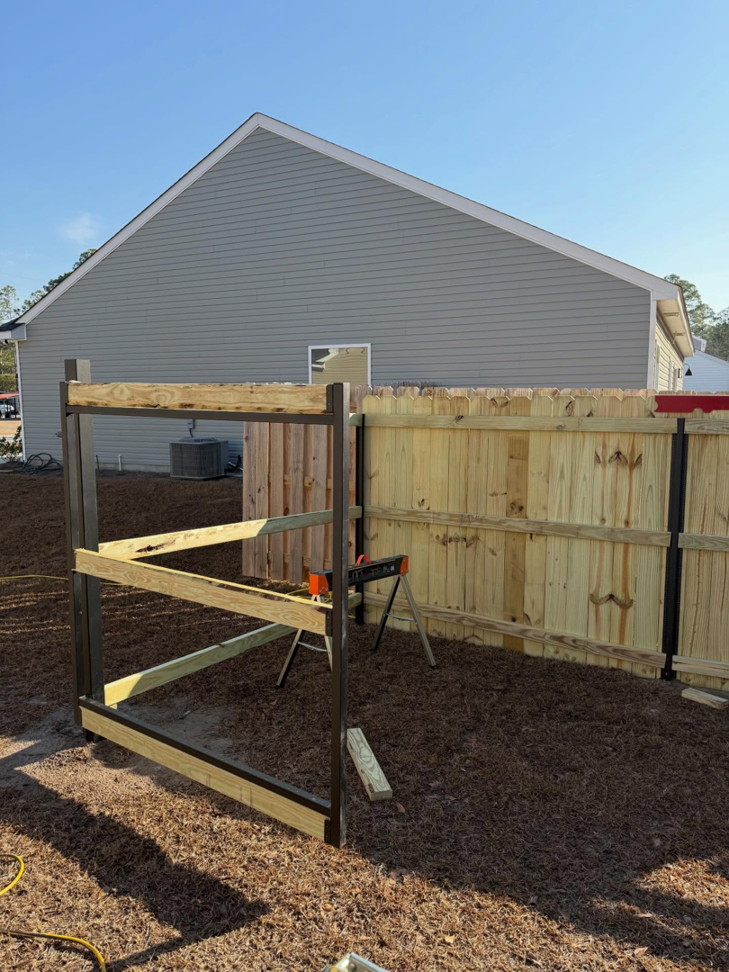 A partially constructed wooden fence with black metal posts in a backyard by JBunlimitedfencingllc in Savannah, GA.