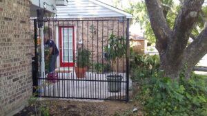 A black metal fence enclosing a patio area next to a brick house, installed by Dallas Mobile Welder, LLC. in Dallas, TX.