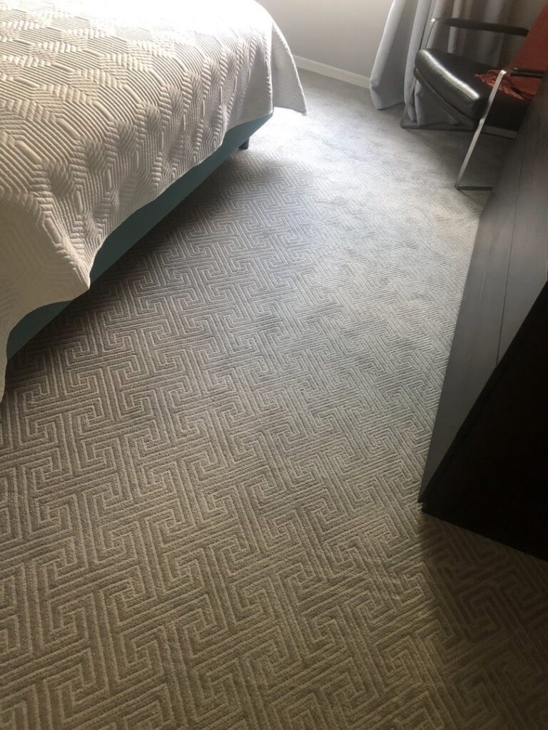 A close-up view of a bedroom with stylish patterned carpet, expertly installed by B A Carpet and Flooring in Broken Arrow, OK.