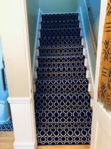 A stylish dark patterned carpet runner expertly installed on a staircase by Zelo Flooring in San Diego, CA.