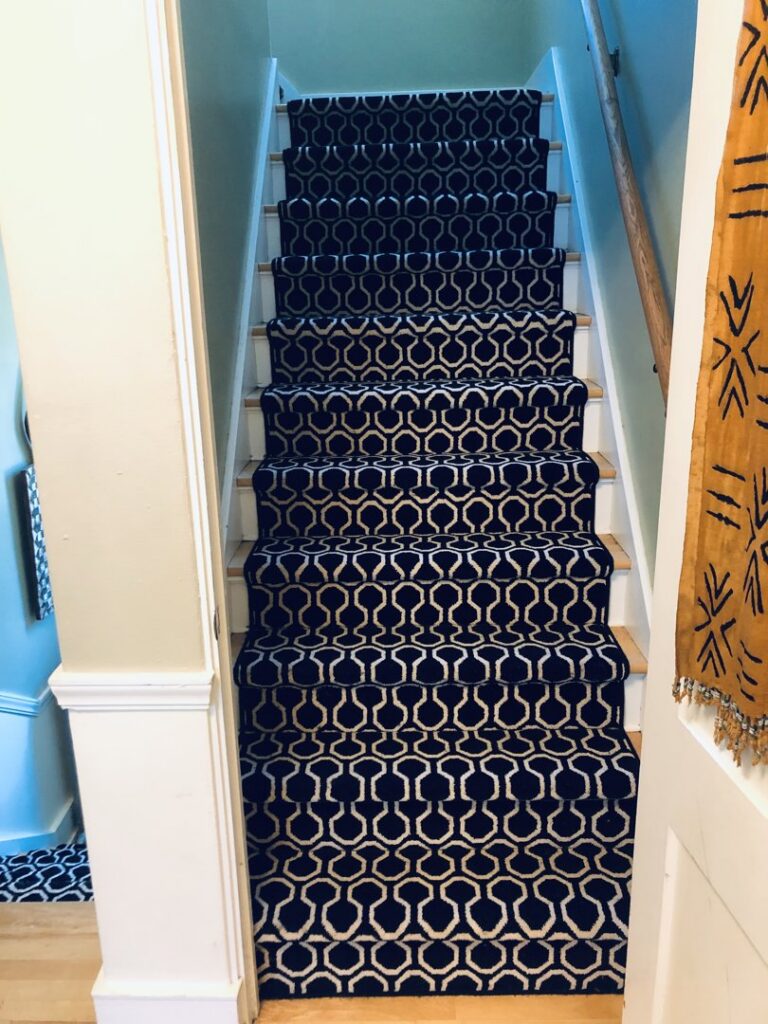 A stylish dark patterned carpet runner expertly installed on a staircase by Zelo Flooring in San Diego, CA.