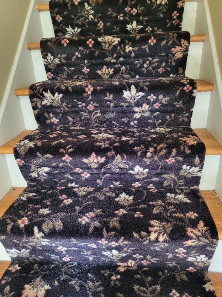A beautifully installed patterned carpet runner on wooden stairs by Greenco2, a carpet contractor in Grand Rapids, MI.