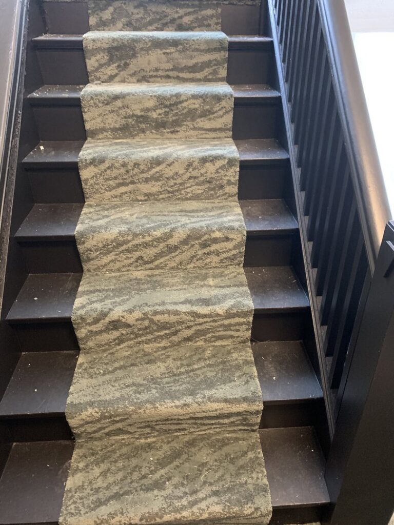 A staircase with a newly installed green and grey patterned carpet runner by Flooring Xpress Enterprise in Chicago, IL.