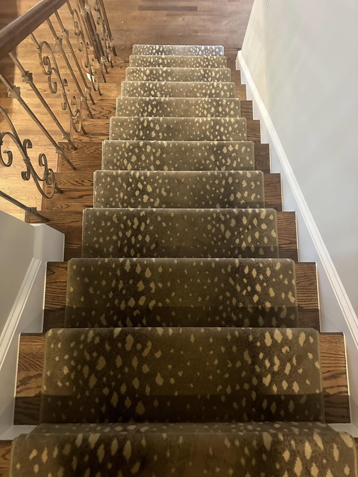 A beautifully installed patterned carpet runner on a wooden staircase by On Point Flooring in Concord, NC