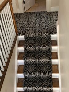 An elegant staircase with a patterned carpet runner installed by Red carpet&home remodeling, your carpet contractor in Olney, MD.