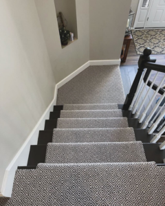 A beautifully installed patterned carpet runner on a dark wood staircase by Rosas Carpet & Flooring in Shorewood, IL.