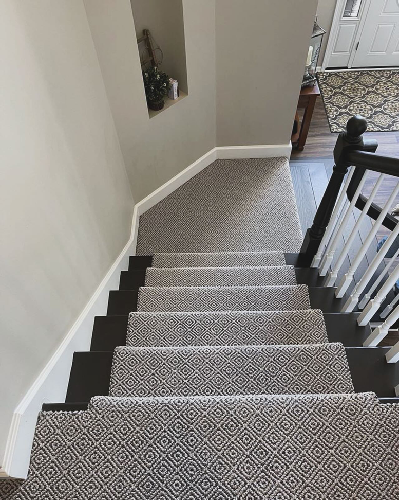 A beautifully installed patterned carpet runner on a dark wood staircase by Rosas Carpet & Flooring in Shorewood, IL.