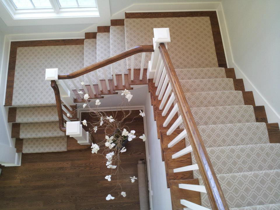 A beautifully installed patterned carpet runner on a wooden staircase by Carpet Art of America in O'Fallon, MO.