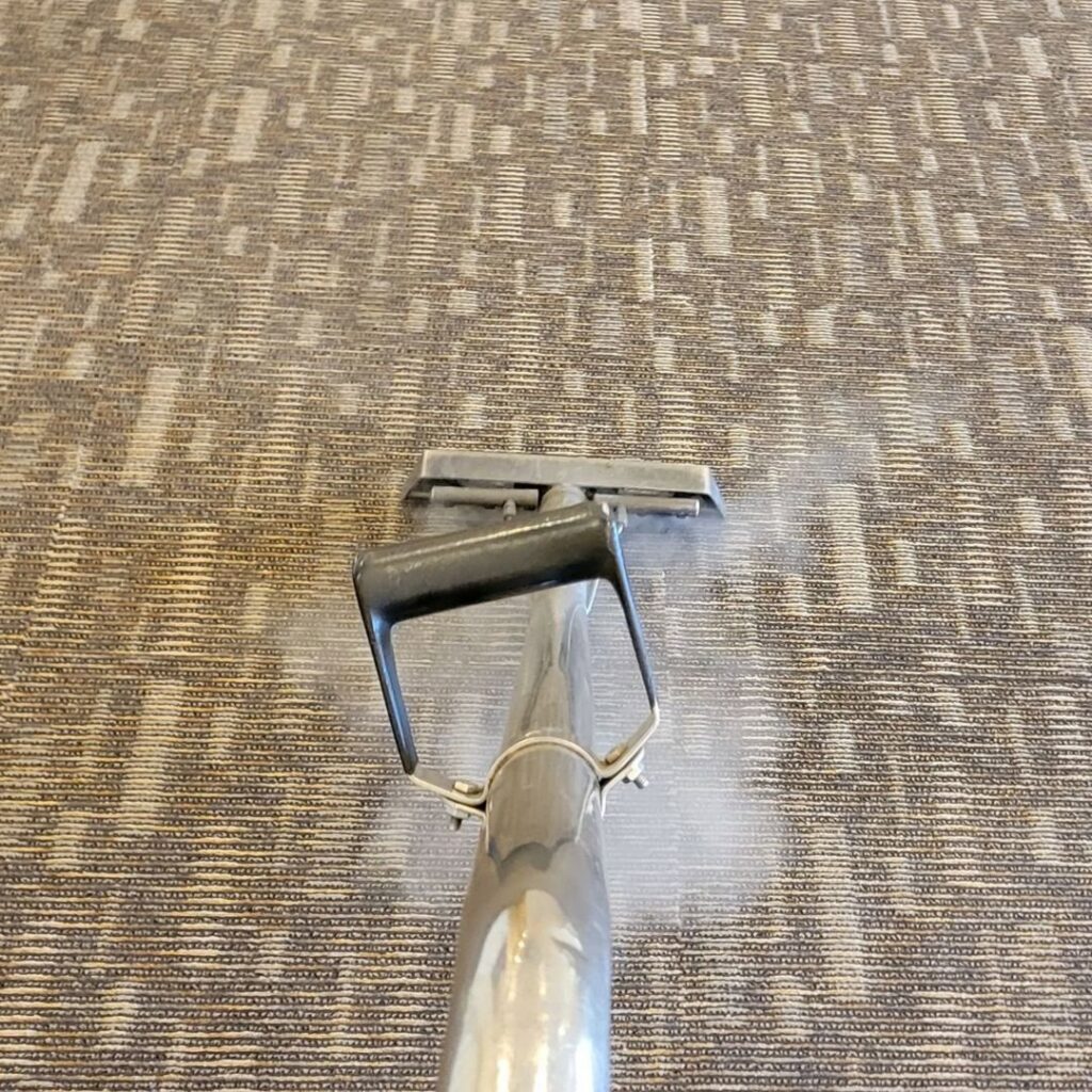 A carpet cleaning wand steam cleaning a patterned carpet by Ardent Carpet Restore in Sacramento, CA.