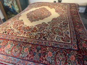 A patterned rug laid out on a floor with rolled carpet or padding materials, suggesting installation by Danvers Rug in Danvers, MA.